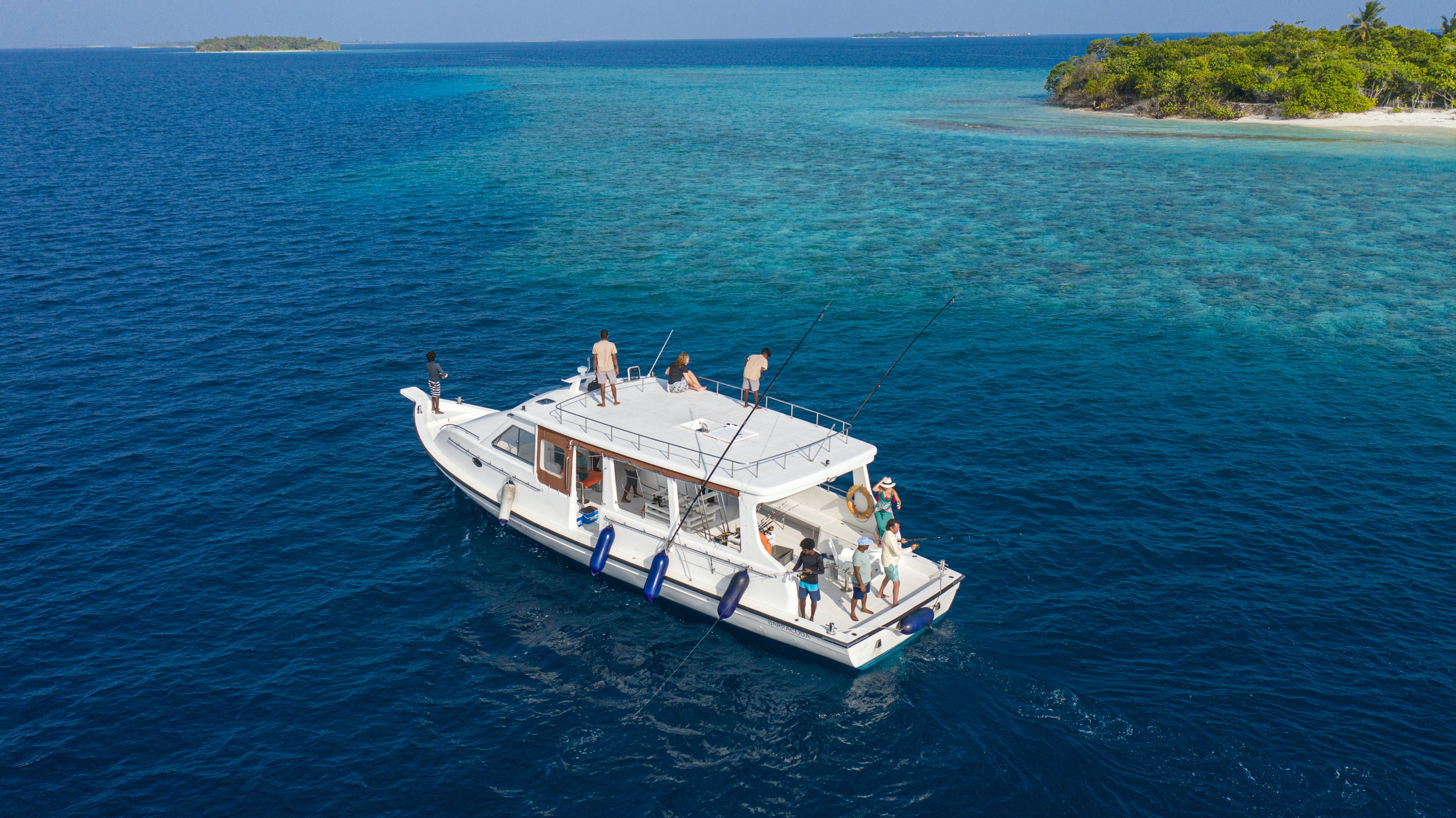 A white boat on blue water near a small island with green trees.